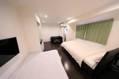 a bedroom with two beds and a flat screen tv at \u30a2\u30f3\u30c9\u30b9\u30c6\u30a4\u3059\u3082\u3046\u30db\u30c6\u30eb401 in Tokyo