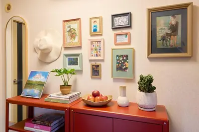 a table with a bowl of fruit on a wall with pictures at Liberty house 7ppl in Tokyo