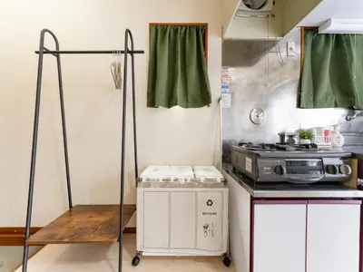 a small kitchen with a stove and green curtains at Kosuge Sta 6min walk Ueno Sta 10min Switch in Tokyo