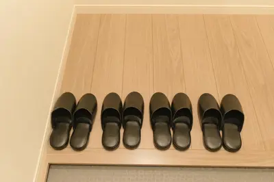 a row of black shoes on a wooden shelf at Victoria \u4e0b\u5317\u6ca2 by Tranova in Tokyo