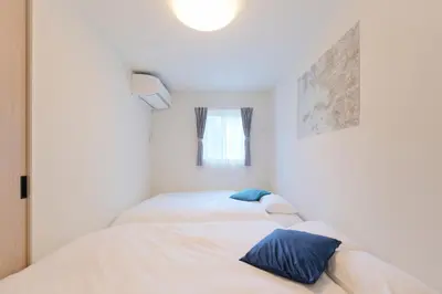 two beds in a white room with blue pillows at Victoria \u4e0b\u5317\u6ca2 by Tranova in Tokyo