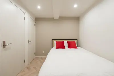 a bedroom with a white bed with red pillows at LaVie\u56db\u8c37 in Tokyo