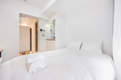 a white bed with white sheets and towels on it at 67 Apt Kinshicho in Tokyo