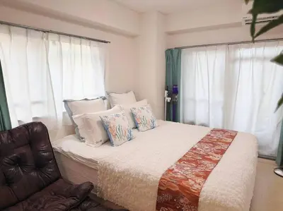 a bedroom with a bed with pillows and a chair at \u5143\u685c\u4e0a\u91ce\u6d45\u8349\u9ad8\u7d1a\u6c11\u6cca\u6700\u59278\u4eba\u99c56\u5206\u9ad8\u7d1a\u30d6\u30e9\u30f3\u30c9\u30d9\u30c3\u30c9\u5bb6\u5ead\u6620\u753b\u9928\u7121\u6599\u81ea\u8ee2\u8eca in Tokyo