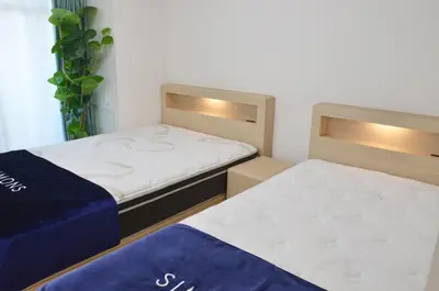 two beds in a small room with blue sheets at \u5143\u685c\u4e0a\u91ce\u6d45\u8349\u9ad8\u7d1a\u6c11\u6cca\u6700\u59278\u4eba\u99c56\u5206\u9ad8\u7d1a\u30d6\u30e9\u30f3\u30c9\u30d9\u30c3\u30c9\u5bb6\u5ead\u6620\u753b\u9928\u7121\u6599\u81ea\u8ee2\u8eca in Tokyo