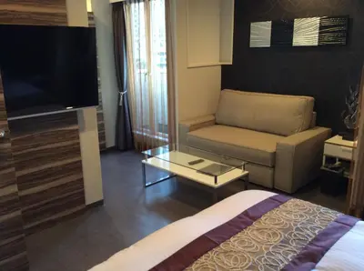 a hotel room with a bed and a couch and a tv at Amand Hotel in Tokyo
