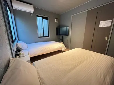 a room with two beds and a flat screen tv at Rakuna Inn \u967d Sasazuka2 in Tokyo