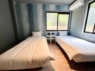 two beds in a room with two windows at Rakuna Inn \u967d Sasazuka2 in Tokyo