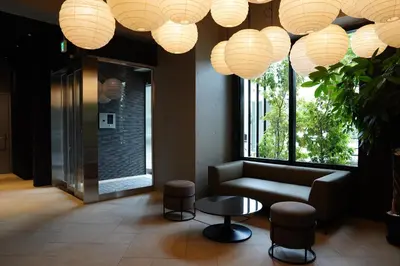 a lobby with a couch and a table and lights at MUSASHI Residence Morisita Station Front in Tokyo
