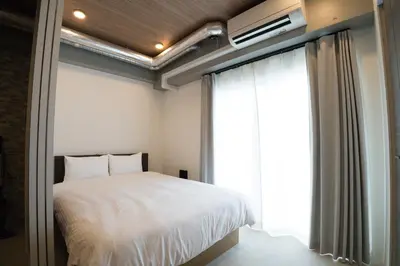 a bedroom with a white bed and a window at MUSASHI Residence Morisita Station Front in Tokyo