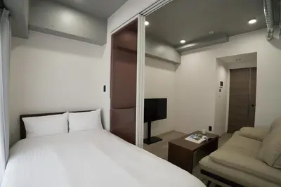 a bedroom with a bed and a couch and a television at MUSASHI Residence Morisita Station Front in Tokyo