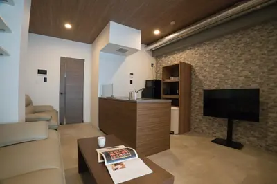 a living room with a couch and a tv and a table at MUSASHI Residence Morisita Station Front in Tokyo