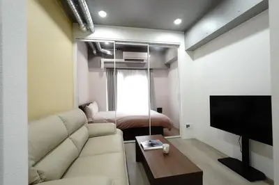 a living room with a couch and a bed at MUSASHI Residence Morisita Station Front in Tokyo
