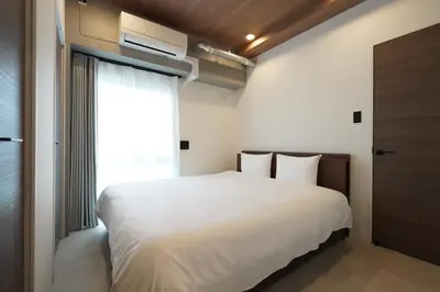 a bedroom with a large white bed and a window at MUSASHI Residence Morisita Station Front in Tokyo