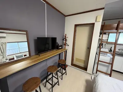 a room with a bar with two stools and a television at Kita LOVE House in Tokyo