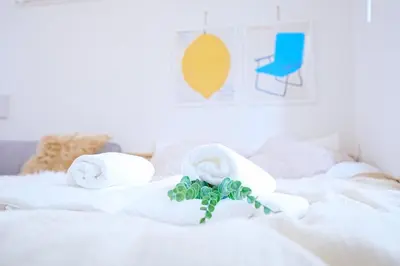 a white bed with towels and a blue chair at Nordic-Retreat Inn in Tokyo