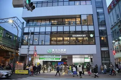 a crowd of people crossing a street in front of a building at \u65b0\u5bbf\u306e\u5bbf in Tokyo