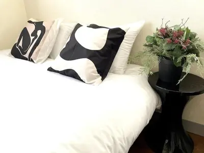 a bed with black and white pillows and a plant on a table at \u65b0\u5bbf\u306e\u5bbf in Tokyo