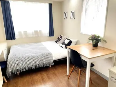 a bedroom with a bed and a desk and a window at \u65b0\u5bbf\u306e\u5bbf in Tokyo
