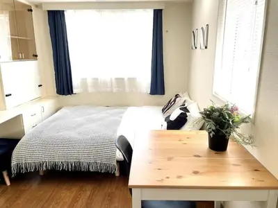 a bedroom with a bed with a table and a window at \u65b0\u5bbf\u306e\u5bbf in Tokyo