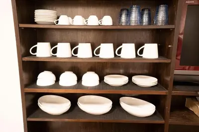 a shelf filled with white bowls and plates at Jarudan in Tokyo