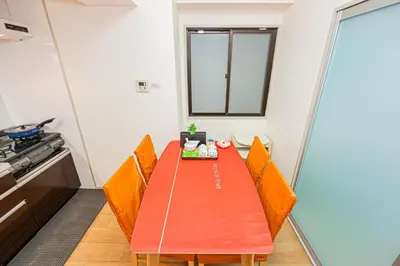 a dining room with an orange table and chairs at KYARA Hotel\u30df\u30b9\u30df202 in Tokyo