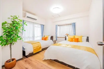 a bedroom with two beds and a potted plant at KYARA Hotel\u30df\u30b9\u30df202 in Tokyo