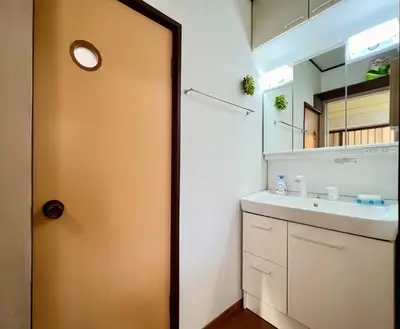 a bathroom with a sink and a door with a mirror at FUKU House in Tokyo