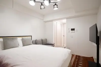 a bedroom with a white bed and a flat screen tv at MAT Shinjuku West in Tokyo