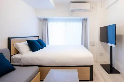 a bedroom with a bed and a tv and a couch at MAT Shinjuku West in Tokyo