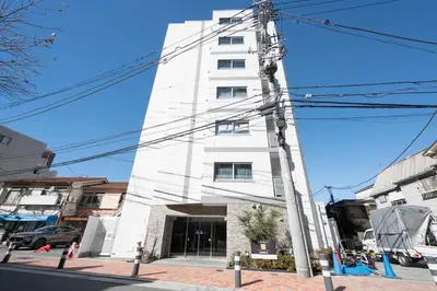 a white building on a city street with power lines at MAT Shinjuku West in Tokyo