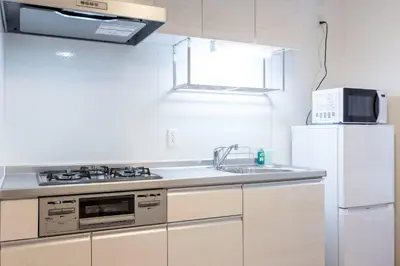 a kitchen with a sink and a white refrigerator at skye yusima in Tokyo