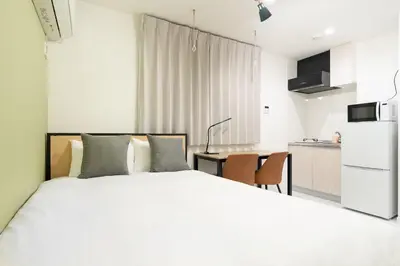 a bedroom with a white bed and a kitchen at Luna\u4e21\u56fd in Tokyo