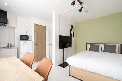 a bedroom with a bed and a table and a kitchen at Luna\u4e21\u56fd in Tokyo