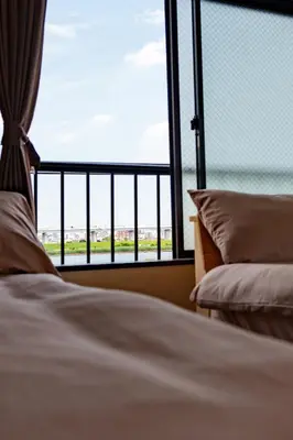 a bedroom with a bed and a large window at \u58a8\u7530\u533a\u76f4\u8fbe\u6cb3\u666f\u6c11\u5bbf in Tokyo