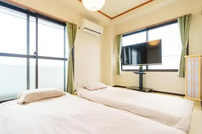 two beds in a room with windows and a flat screen tv at \u58a8\u7530\u533a\u76f4\u8fbe\u6cb3\u666f\u6c11\u5bbf in Tokyo