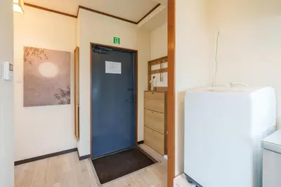 a room with a blue door and a refrigerator at \u58a8\u7530\u533a\u76f4\u8fbe\u6cb3\u666f\u6c11\u5bbf in Tokyo