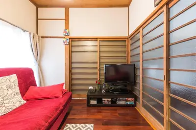 a living room with a red couch and a tv at Samurai House - Vacation STAY 54179v in Tokyo