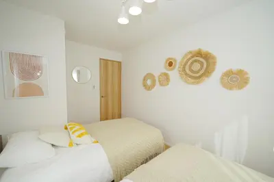 two beds in a room with white walls at Jacky's House Yahiro in Tokyo