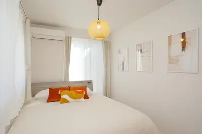 a bedroom with a white bed with orange and yellow pillows at Jacky's House Yahiro in Tokyo