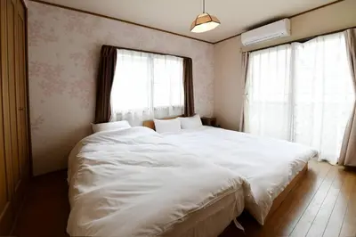 a bedroom with a large white bed with two windows at Largo in Tokyo