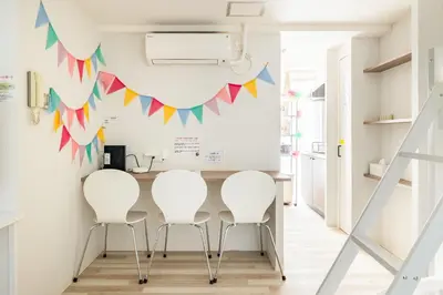 a dining room with white chairs and a table with flags on the wall at Shibuya WAVE 201 in Tokyo
