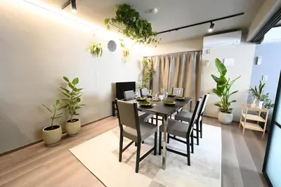 a dining room with a table and chairs and plants at NiHITARU Stay in Tokyo