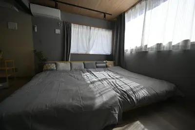 a large bed in a bedroom with a large window at NiHITARU Stay in Tokyo