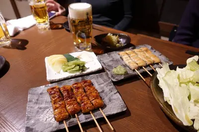 a wooden table with food on skewers on a table at Shateray Yoyogi 301 in Tokyo