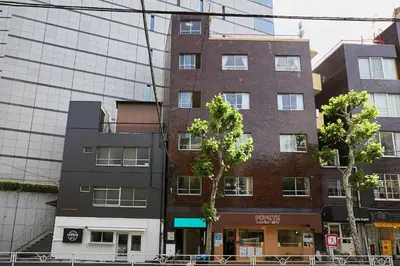 a tall brick building in front of a glass building at Shateray Yoyogi 301 in Tokyo