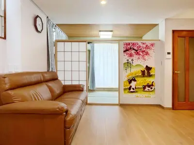 a living room with a brown couch and a window at WE Hotel Family House in Tokyo