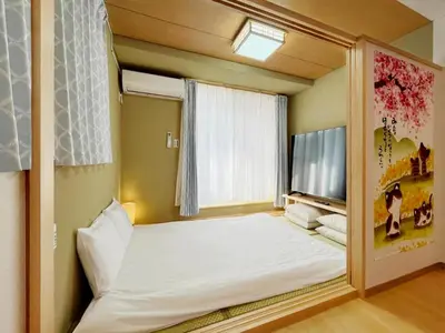 a bedroom with a large white bed and a tv at WE Hotel Family House in Tokyo