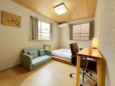 a small room with a bed and a couch and a desk at WE Hotel Family House in Tokyo