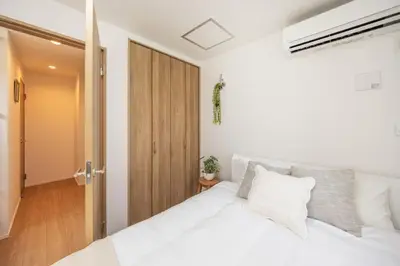 a bedroom with a white bed and a wooden door at \u6771\u4eac\u65b0\u7bc985\u5e73\u7c73\u99c5\u5f92\u6b696\u5206\u6700\u59278\u540d\u7121\u6599\u99d0\u8eca\u5834\u6771\u4eac\u4e0a\u91ce\u79cb\u8449\u539f\u99c5\u76f4\u901a in Tokyo